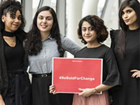 Apprentices holding #BeBoldForChange board