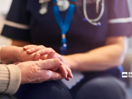 Nurse holding older person's hands