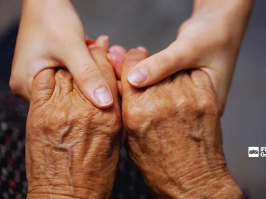 Older person and young person holding hands with the IFB Gaming logo in the corner