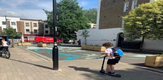 Cultivating cally environment child in a scooter riding into on the pavement next to a play area