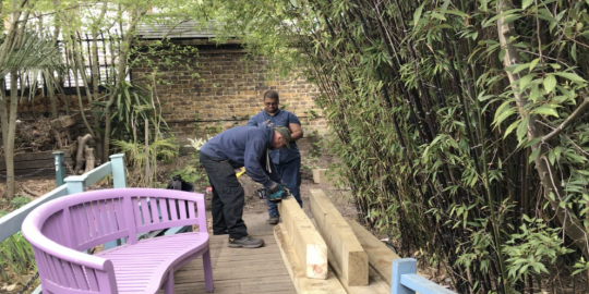 New cross nurturing nature infrastructure environment two people working on timber wood inside a garden area