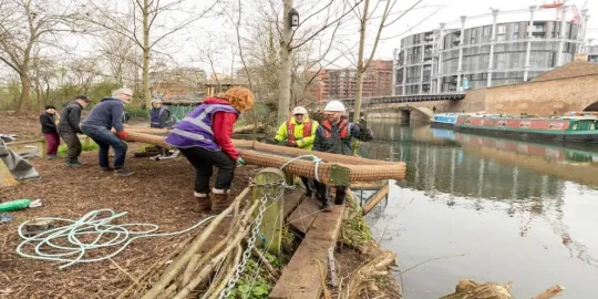 Regents canal green environment with people lifting a raft into the water 