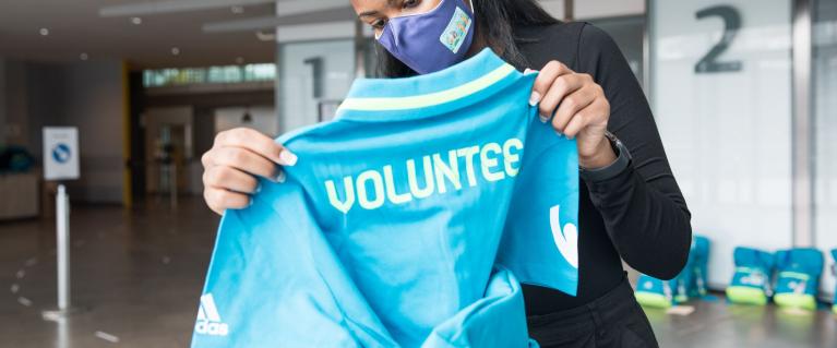 Team London volunteer holding a blue volunteer t-shirt for Euro2020