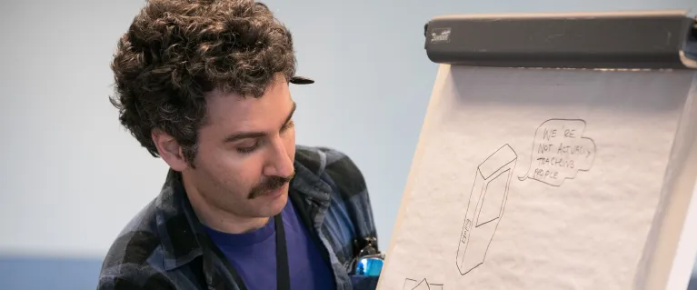Man writes on a large paper note board