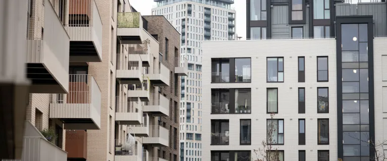 Modern black, white and tan blocks of flats, with square glass windows and balconies.