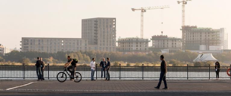 People walking and cycling by the docks in the context of emerging new development in the Royal Docks