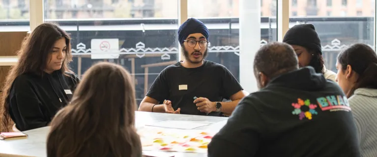 Young people sitting around a desk discussing ideas.