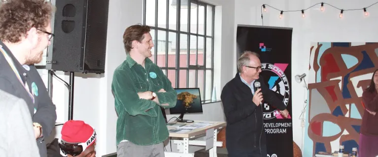  Image of 3 people standing next to a man holding a microphone