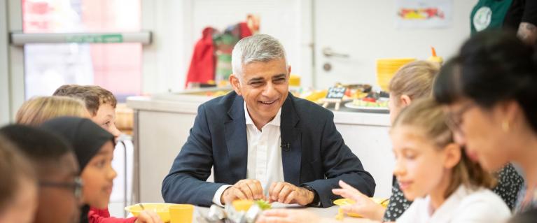 The Mayor Sadiq Khan with children around a table eating a meal