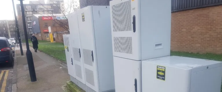 (5G equipment boxes) Three white digital connectivity equipment boxes located on pavement