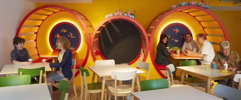 Photo of the theatre cafe's colorful train seating, with families and children