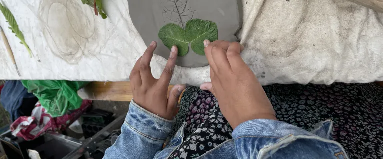 A girl making copies of leaves in clay during an art workshop 