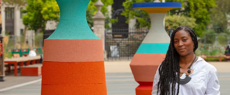 Simone Brewster poses next to colourful graphic sculptures in a public square