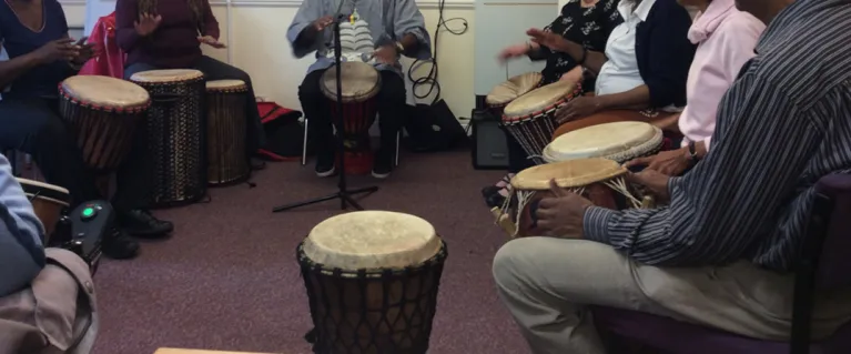Group of people sat in a circle playing hand drums