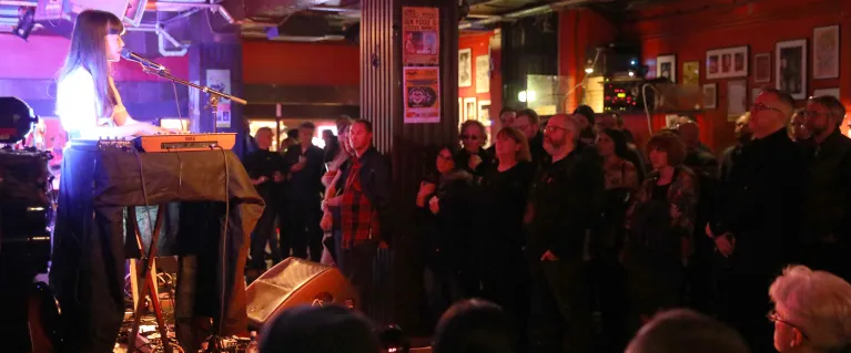 Audience watching live performance of a woman singing and mixing music