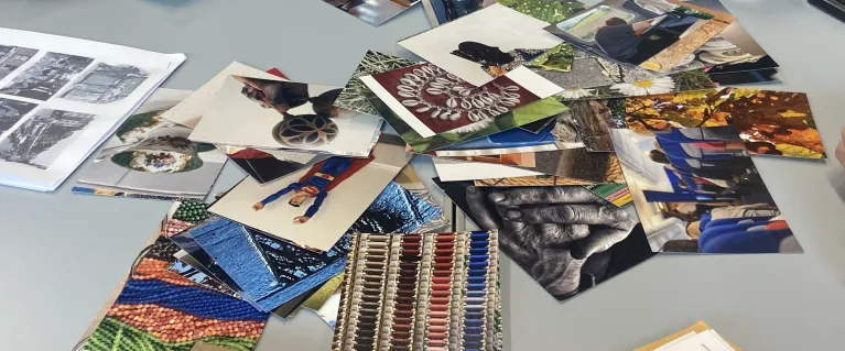 An older person sat at a table with photographs and books
