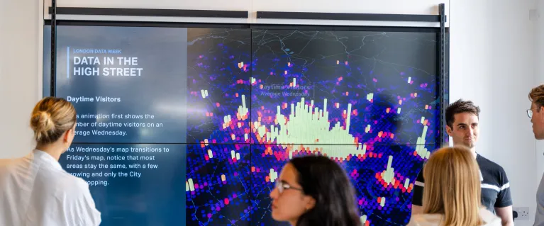 People standing around a screen displaying a data map