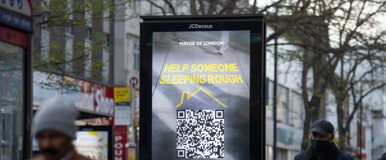 man walking past rough sleeping advertisement board
