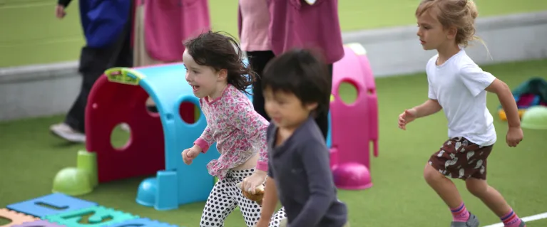 3 children racing outside on the school track