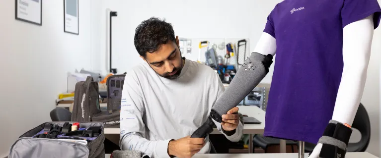 Image of a man working in a lab, creating a prosthetic arm