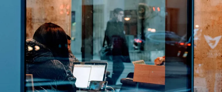 Person in cafe using laptop and phone