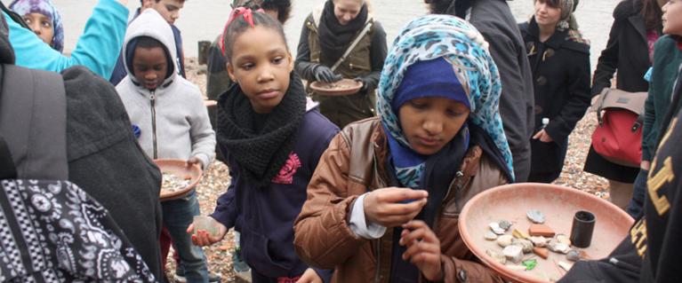 Schoolchildren collect pebbles on a beach