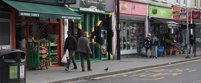 A photo of a high street in London with shops and members of public