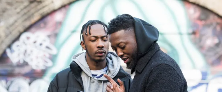 Two young black men using a camera