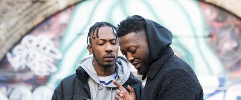Two young black men using a camera