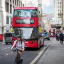 A red London bus and a cyclist on a London street