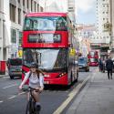 A red London bus and a cyclist on a London street