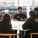 Young people sitting around a desk discussing ideas.