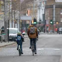 An adult cycling with their child on a London road