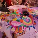 A group of participants colouring in a large illustration on a table during the Rewire summit.