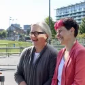Zoe Garbett and Caroline Russell standing outside of City Hall smiling at a Londoner. 