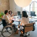 Three people sit at a table having a conversation.