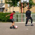 Young boys playing football on a concrete surface.