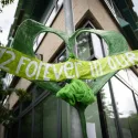 Close up of a green heart shape attached to a pole. The heart has a banner across its middle reading 72 forever in our hearts 
