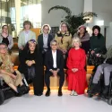 Group of 11 people, with two people in wheelchairs sat on benches looking at the camera.