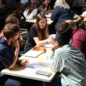 Small groups of people sat at tables with notebooks and pens discussing the High Street Network at a study visit.