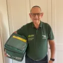 Volunteer in green uniform holding chiller bag