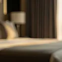 Blurred view of a modern hotel bedroom with warm sunlight streaming through the window