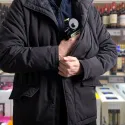 person putting items in supermarket in coat