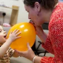 Woman blowing a balloon up for a child