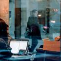 Person in cafe using laptop and phone