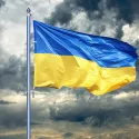 The Ukraine flag raised under a cloudy sky