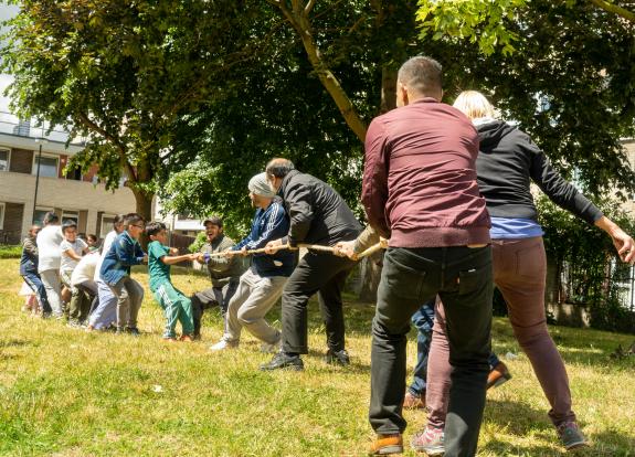 A community group of adults and children playing tug of war