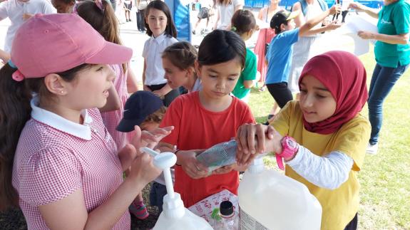Children refilling soap bottles at a school