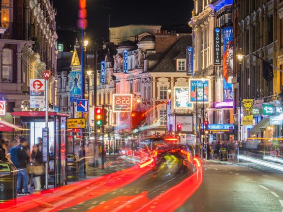 An image showing a lively London street at night with people out and about.