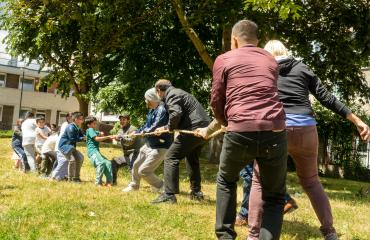 A community group of adults and children playing tug of war